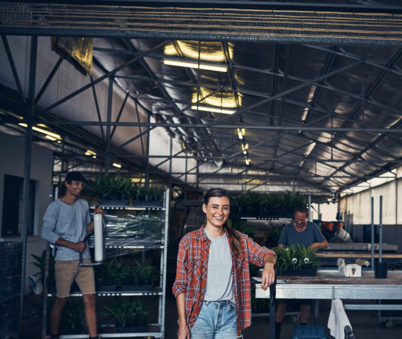 We grew our garden center from the ground up Portrait of a young woman working in a garden center with her coworkers in the background